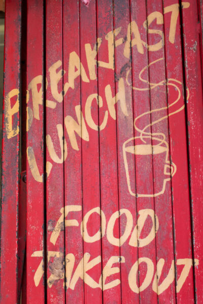 the side of a red building with a cup of coffee painted on it and the words Breakfast Lunch Food Takeout painted around the cup - photo: Victoria Klum Photography