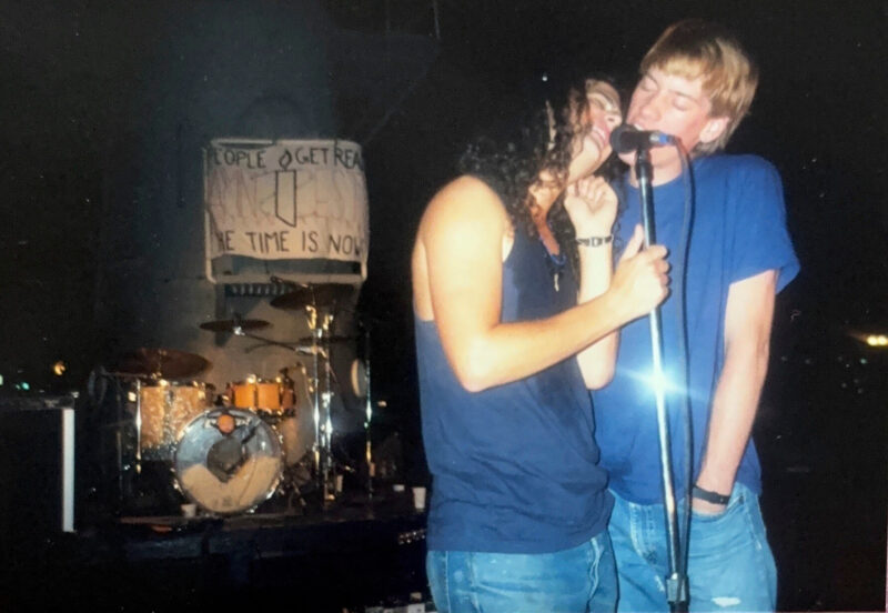Two men are at a microphone singing.