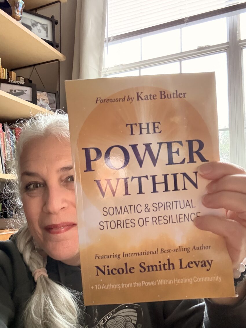 a woman holding up a book titled The Power Within: Somatic & Spiritual Stories of Resilience