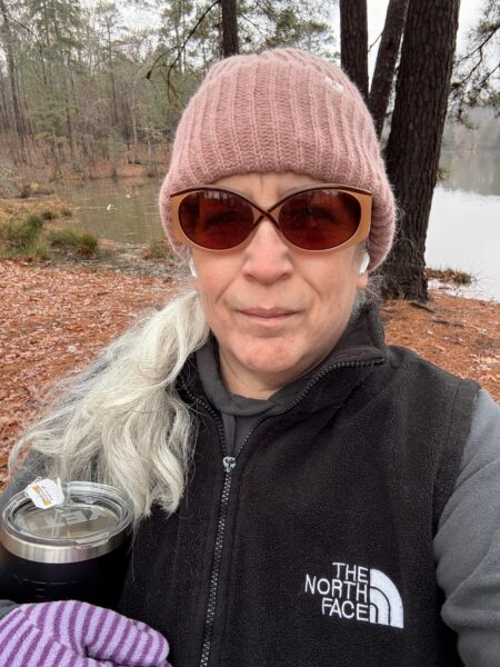 a woman with long white hair wearing a pink beanie and sunglasses
