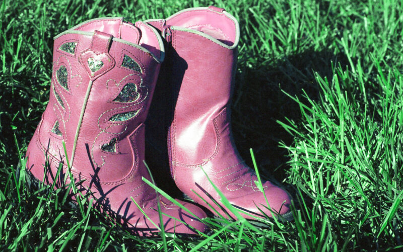 a pair of girl's pink cowboy boots on green grass